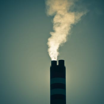 Industrial factory chimney with smoke against sky background. Instagram style shot