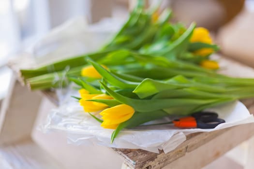 Yellow tulips flowers bouquet on a wooden table. Indoors natural light shot with small depth of field