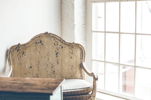 Vintage armchair and a wooden table in a room with white walls and a large window