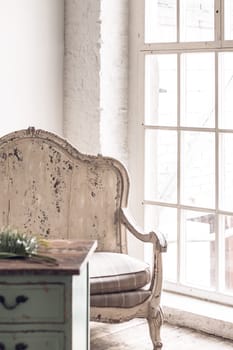Vintage armchair and a wooden table in a room with white walls and a large window