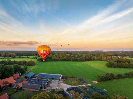 DE LUTTE, NETHERLANDS - AUGUST 21, 2024: Orange hot air balloon searching for a landing spot in a rural landscape