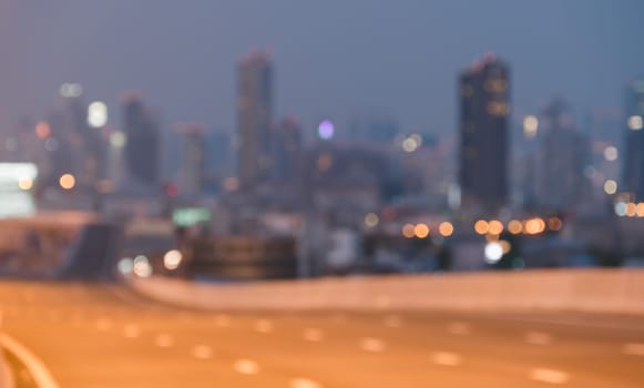 Abstract blurred cityscape at twilight with tall skyscrapers against hazy sky. City building lights twinkle in urban atmosphere background.