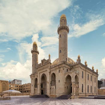 View of the majestic Taza Pir Mosque in Baku, Azerbaijan showcases intricate architecture with twin minarets against a peaceful blue clear sky
