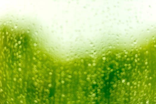 Water drops on a glass surface. Defocused green blur image with bokeh