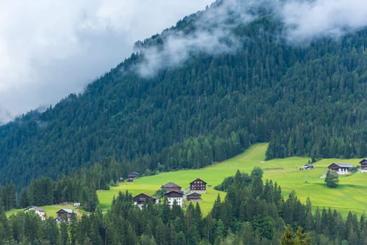 Traditional alpine houses in green forest Alps mountains. Horizontal shot