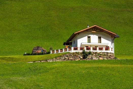 Traditional alpine house on green meadow in summer