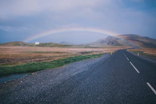Rainbow and Endless Highway through Icelandic landscape. Filtered shot