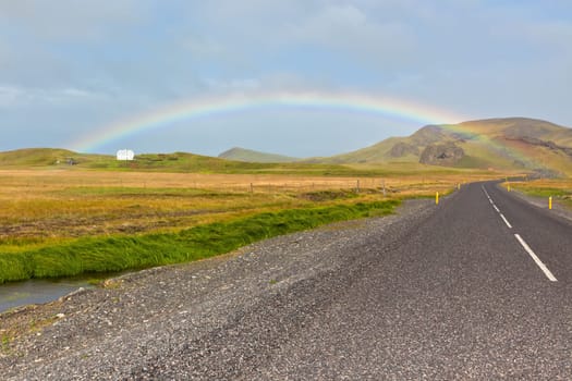 Rainbow and Endless Highway through Icelandic landscape. Filtered shot