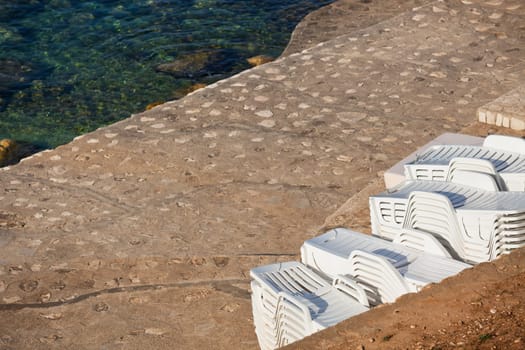 Plastic Poolside Chairs in a pile by the sea
