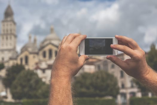 Tourist hands holding smart phone taking photo of Perigueux, France