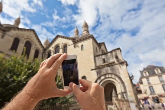 Tourist hands holding smart phone taking photo of Perigueux, France