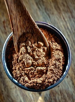 Bowl of cocoa powder on wooden table.