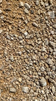 A close-up view of a gravel and earth surface, showcasing a variety of small stones and soil textures in natural earthy tones.