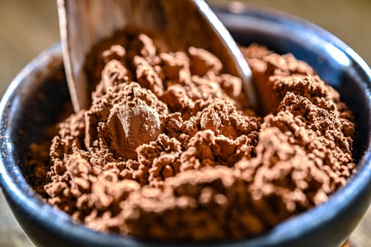 Bowl of cocoa powder on wooden table.