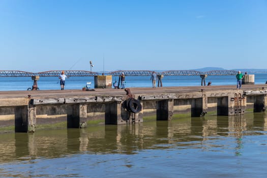 Lisbon, Portugal: April 12, 2024: Fishermen at a pier by the Tagus river near Belem, Lisbon, Portugal