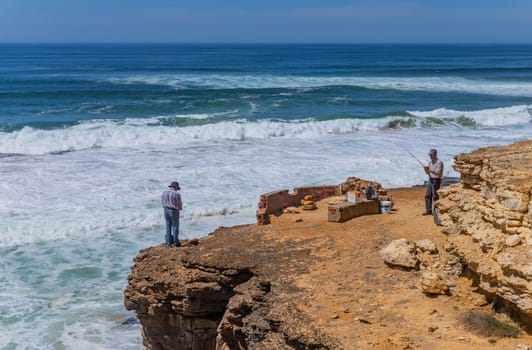 Sintra, Portugal: April 13, 2024: A fishermen stands on the edge of a cliff by the ocean in Ericeira, Portugal