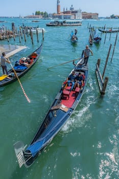 Venice, Italy - July 26, 2024: Gondolas against the San Giorgio island in Venice, Italy. Gondola is the most attractive tourist transport in Venice. Traveling and vacation in sunny Venice.