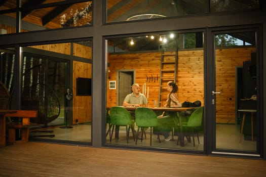 A husband and a wife enjoying conversation in a modern log cabin in the evening