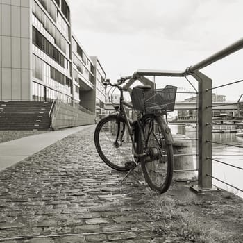 parked bicycle at a fence in the Rheinauhafen in the city of Cologne in Germany in black and white