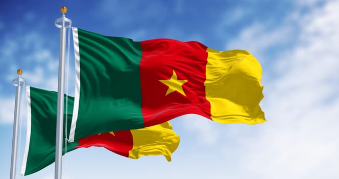 National flags of Cameroon with vibrant green, red, and yellow colors and a central yellow star flaps in the wind against a backdrop of a clear blue sky. 3d illustration render