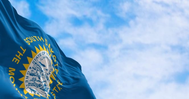 Close-up of the South Dakota flag waving in the wind. Sky blue field, the state seal, and inscriptions of South Dakota and The mount rushmore state. 3d illustration render. Fluttering fabric