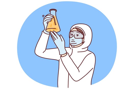 Chemist laboratory assistant holds test tube with reagent examining hazardous substance, dressed in chemical protection clothing. Female chemist examines contents of flask after synthesis