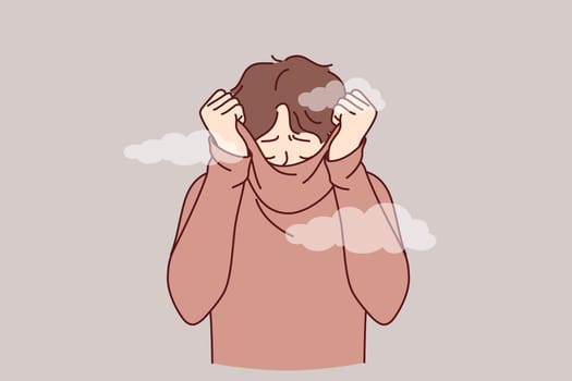Depressed man hides face behind collar of sweater, feeling shame of actions. Upset guy covers head with shame, trying to hide from others and public censure, causing stress and depression