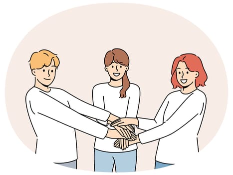 Friendly team of people holding hands demonstrate cohesion and unity, wanting to achieve goals together. Team of young guy and two girls carrying out volunteer or charitable activities