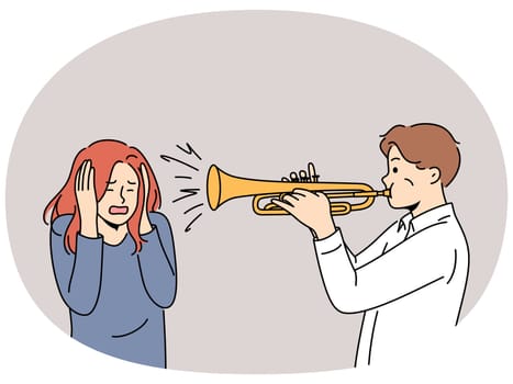 Man plays trumpet near woman covering ears, for concept trumpeter lack musical talent. Guy who wants to become professional musician learns to play compositions on trumpet and interferes with others