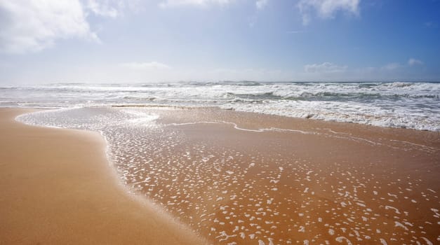 Seascape showing crashing waves from rough surf rolling onto the wet sand following days of bad weather along the coastline on the Sunshine Coast, Kawana, Queensland, Australia