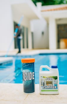 Algaecide and clarifier for swimming pools. Clarifying chemical at the edge of a swimming pool