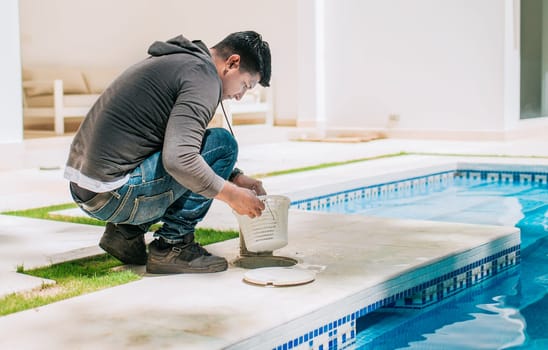 Worker removing trash from swimming pool filter basket. Man cleaning swimming pool garbage filter