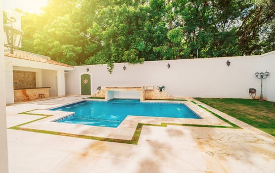 Homemade swimming pool surrounded by nature trees. Beautiful crystal clear swimming pool in a backyard