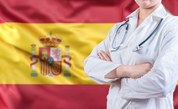 Female doctor with stethoscope on Spain flag. Spanish Health and Care concept. Doctor with arms crossed on Spanish flag