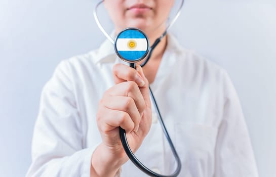 Female doctor holding stethoscope with Argentina flag. Argentine Health and Care concept