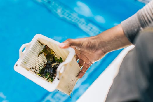 Hand holding swimming pool filter basket. Man cleaning garbage filter basket for swimming pool.