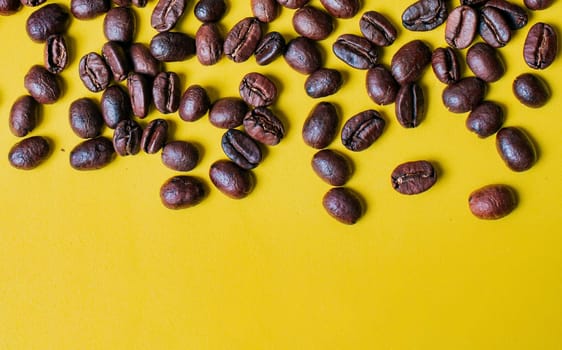 Roasted coffee beans on yellow background with copy space. Coffee grains on yellow background