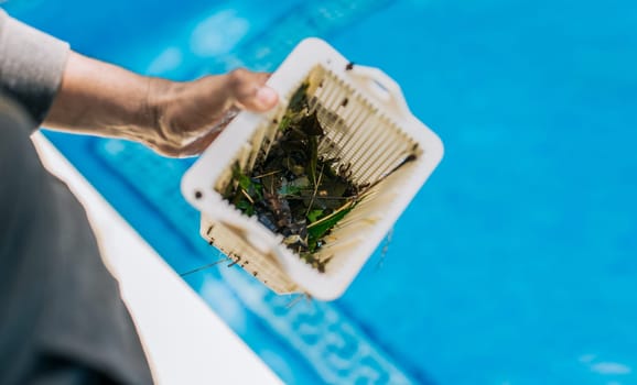 Man cleaning garbage filter basket for swimming pool. trash. Hand holding swimming pool filter basket