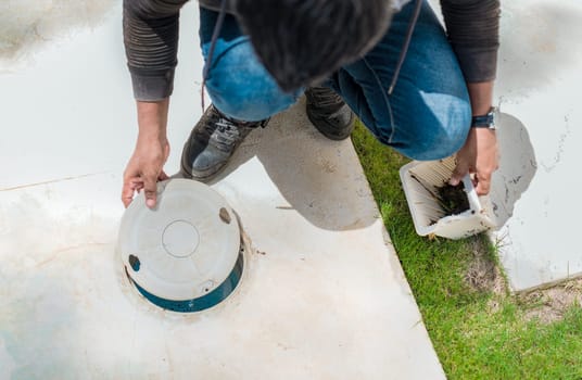 Cleaning and maintenance of the swimming pool skimmer basket. Person cleaning pool filter skimmer basket