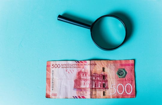 Magnifying glass on isolated 500 cordobas bill. Banknote of 500 cordobas with magnifying glass on isolated background