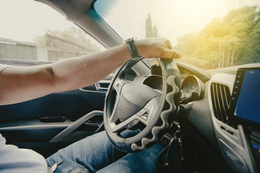 Person hands on the steering wheel driving the car. Close up of hands driving the car