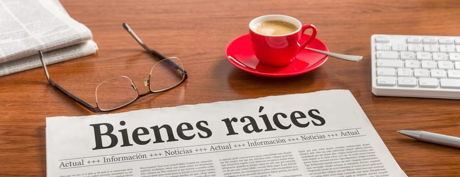 A newspaper on a wooden desk - Real Estate in spanish