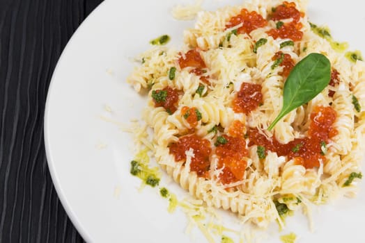 Pasta with parmesan cheese basil and red caviar. The concept of Italian cuisine.
