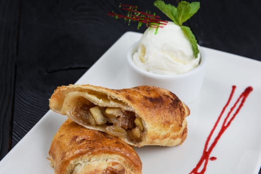 Apple strudel with vanilla ice cream decorated with caramel and berries sauce