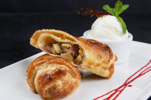 Apple strudel with vanilla ice cream decorated with caramel and berries sauce