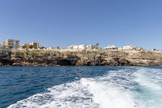 Polignano a Mare, Italy, Apulia - May 24, 2024: View from the water of picturesque coastline with cliffs and caves by Adriatic Sea. Boat cruise along the rocky coast is a great tourist attraction