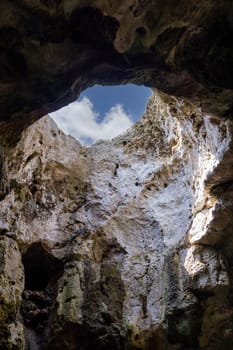 View of the sky from inside the grotto through an opening in the cliff, Polignano a Mare, Italy, Apulia. The city is famous for about 400 water caves visible only from the sea