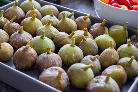 A tray of green figs with brown tips. The figs are arranged in a grid pattern