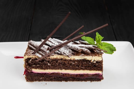 Plate with piece of delicious chocolate cake decorated with mint leaves