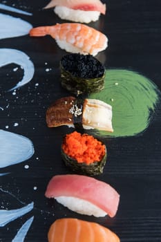 Various kinds of sushi served on wood black table.